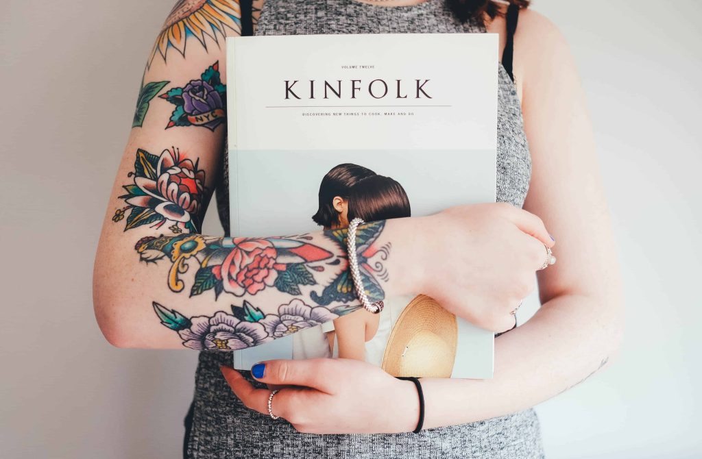 Woman holding a book with tattoos on her right arm