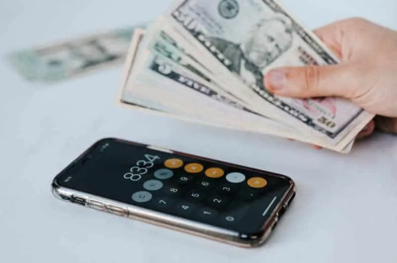 Hand holding dollars banknotes near a calculator