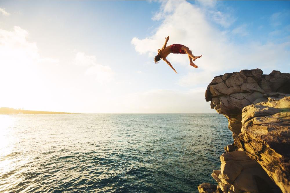 Image via Canva - cliff diver backflipping